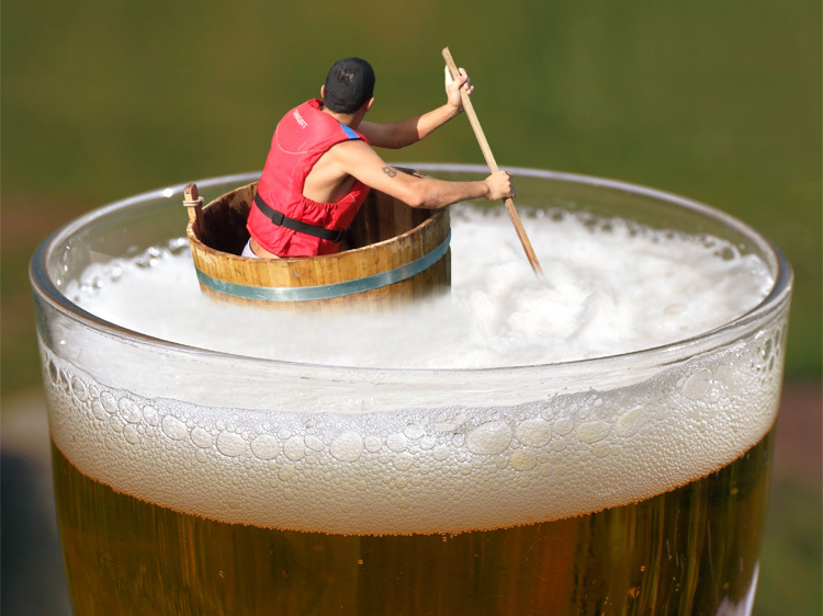 man adrift in giant glass of beer